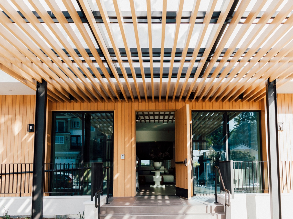 Modern building entrance featuring overhead wood louvers for shade and style